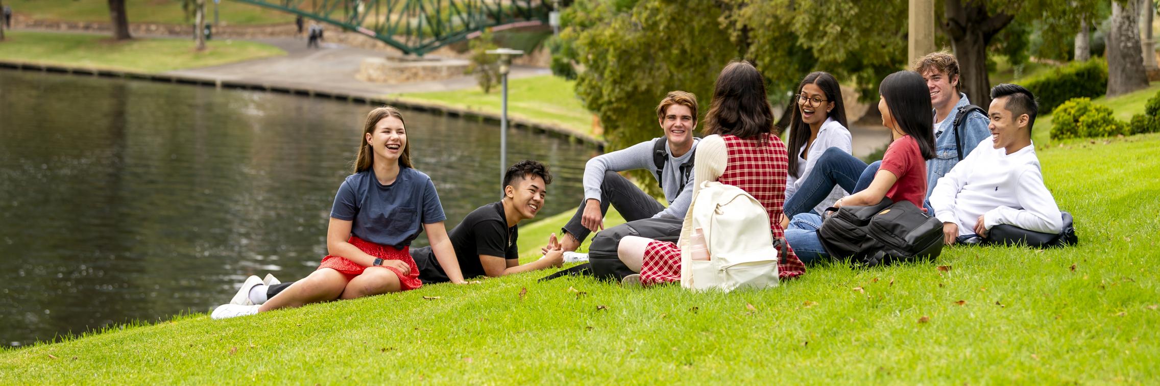 Students sitting by the Torrens