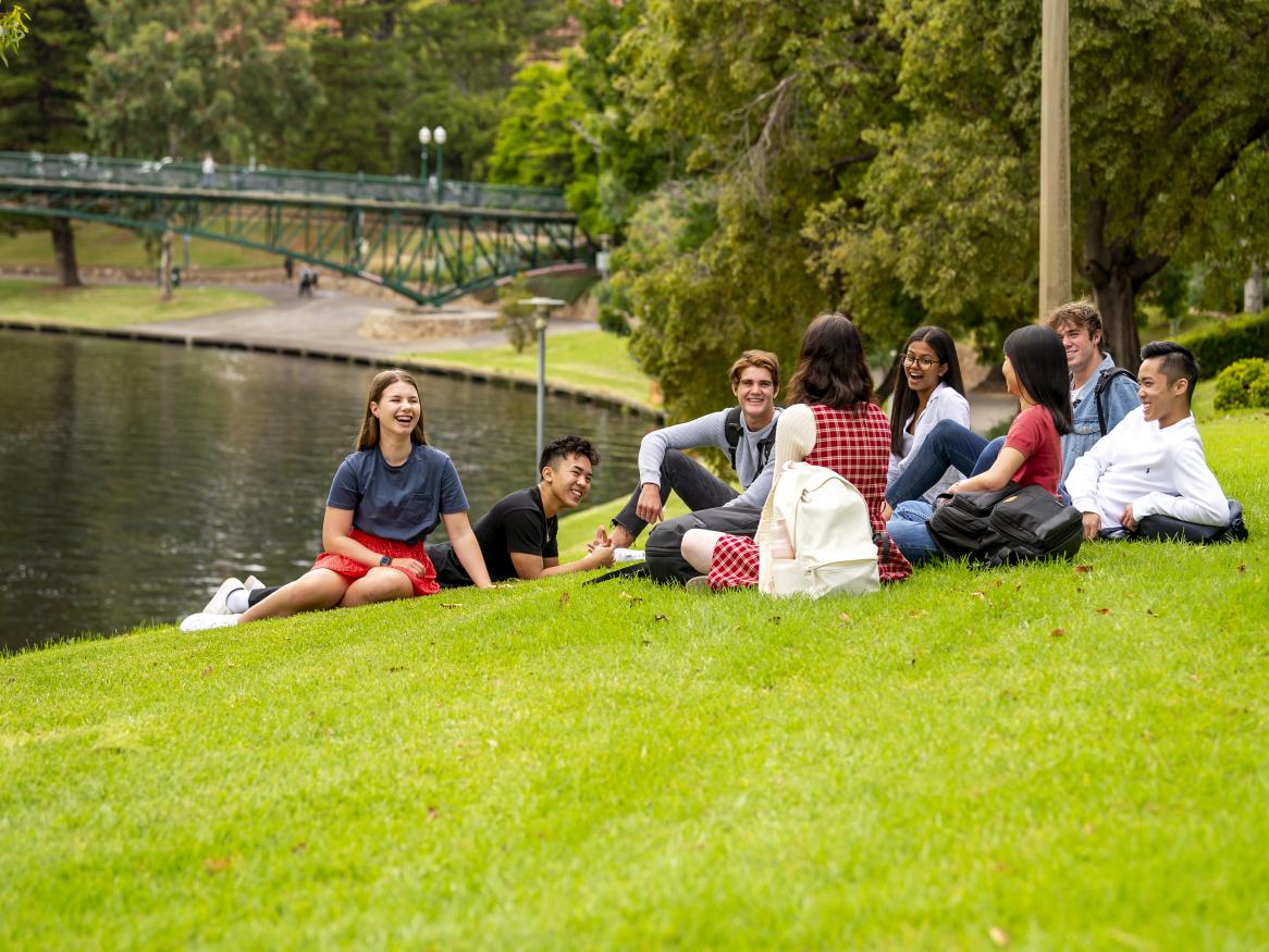 Students sitting by the Torrens